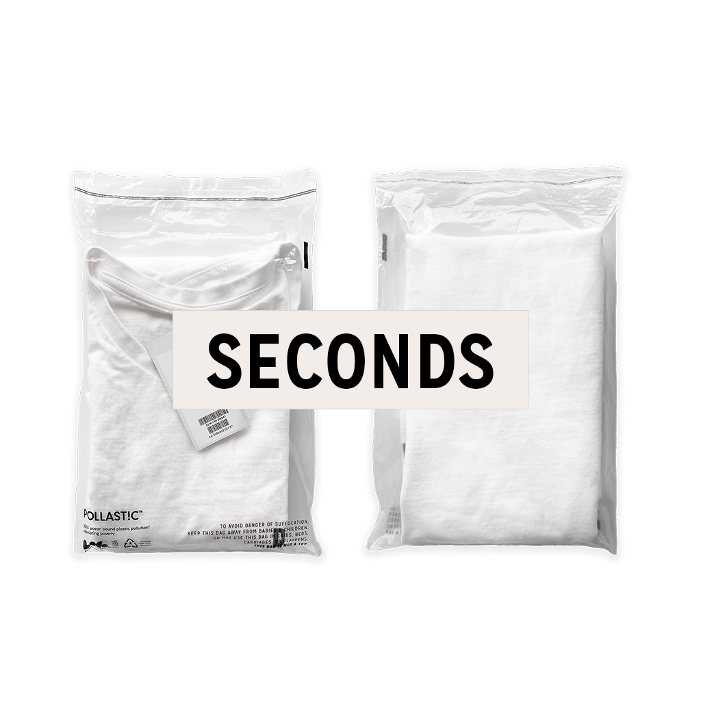 Front and back of a transparent Better Packaging POLLAST!C poly garment bag, containing a white tee shirt on a transparent background with a graphic label "Seconds"