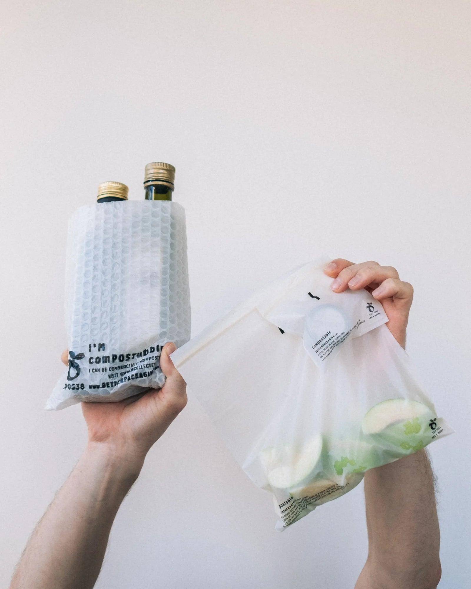 Hands holding up compostable bubble pockets and compostable ziplock bags